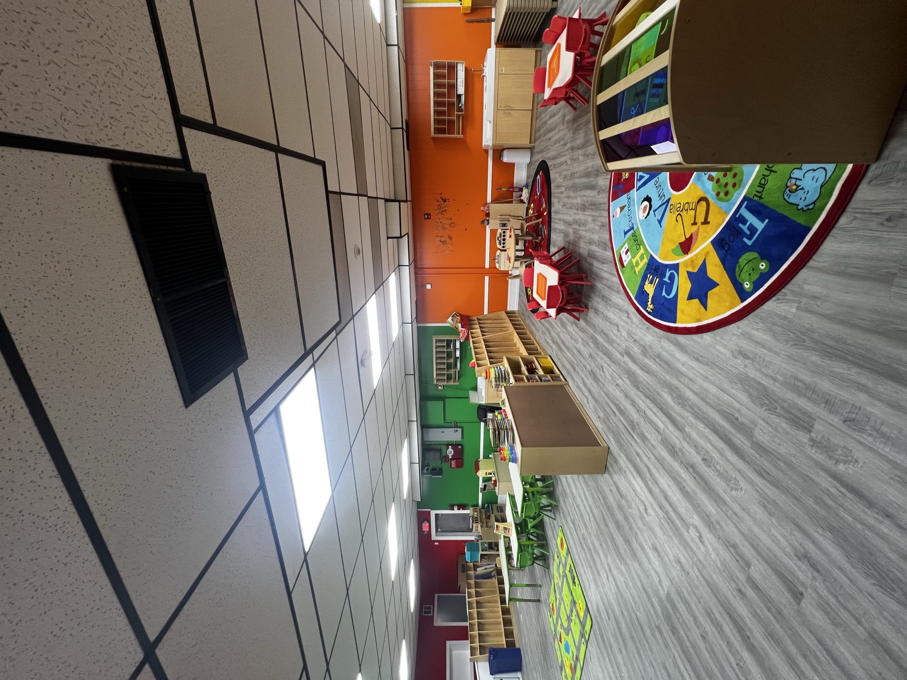 Childcare classroom with gray plank flooring and organized learning areas