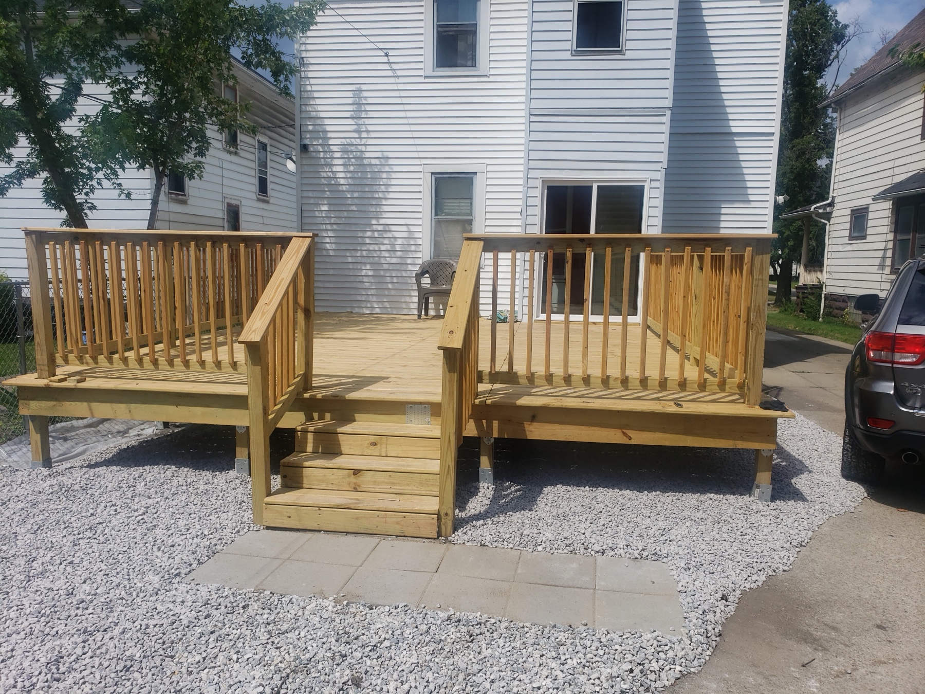 New pressure-treated back deck with wood railing, stairs, and paver landing